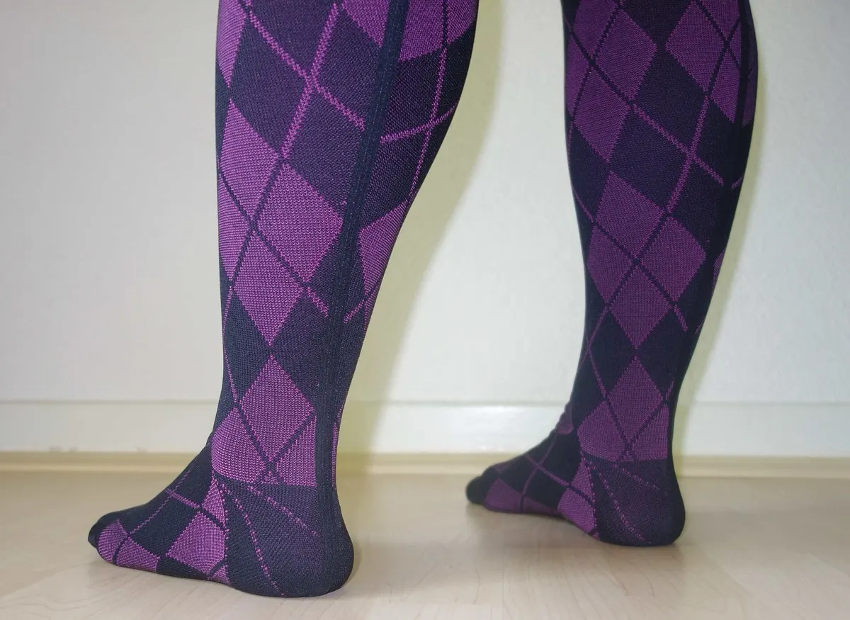 Rear view of a person's calves in purple and navy argyle compression socks, standing on a light wooden floor